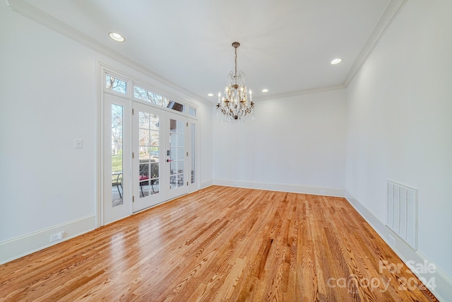 spare room featuring a notable chandelier, french doors, crown molding, and light hardwood / wood-style flooring