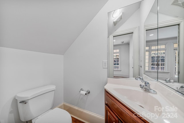 bathroom featuring vanity, vaulted ceiling, and toilet