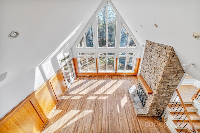 unfurnished living room with a fireplace, light hardwood / wood-style floors, and high vaulted ceiling