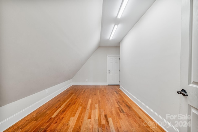 additional living space featuring light wood-type flooring and vaulted ceiling