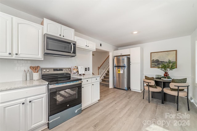 kitchen featuring backsplash, light hardwood / wood-style flooring, white cabinets, and stainless steel appliances