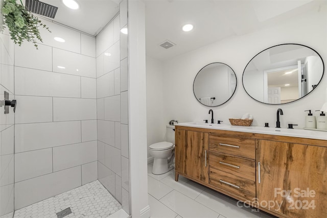 bathroom with tile patterned floors, vanity, toilet, and a tile shower