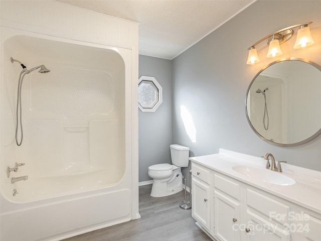 full bathroom featuring bathtub / shower combination, vanity, a textured ceiling, hardwood / wood-style floors, and toilet