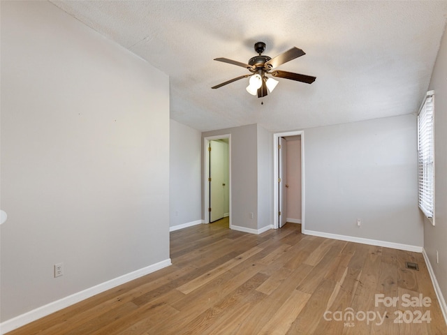 unfurnished room featuring a textured ceiling, light wood-type flooring, and ceiling fan