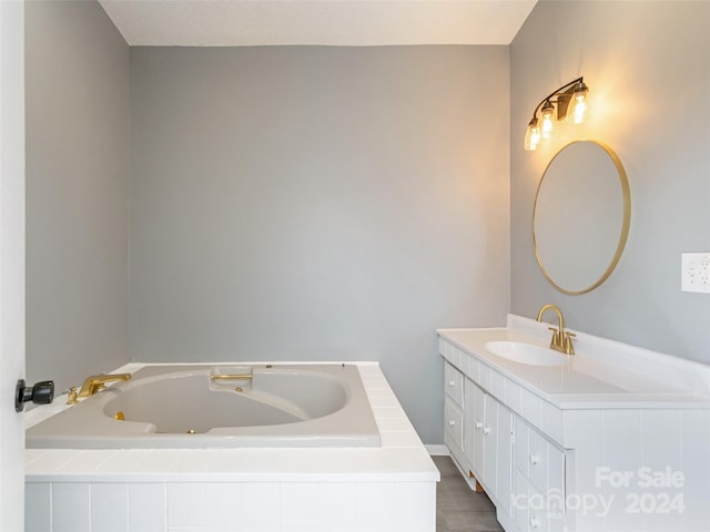 bathroom with vanity and tiled tub