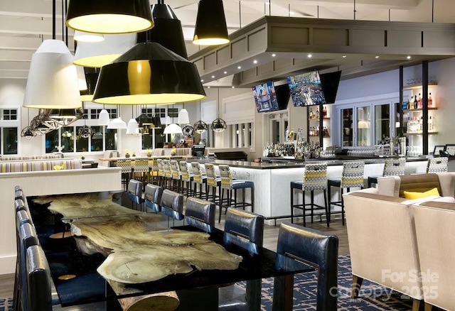 interior space with wood-type flooring, a towering ceiling, and bar area