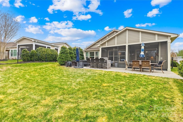 rear view of property featuring a lawn, a sunroom, and a patio area