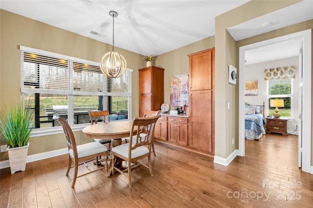 dining space with light hardwood / wood-style flooring and a chandelier