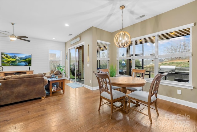 dining area with wood-type flooring and ceiling fan with notable chandelier