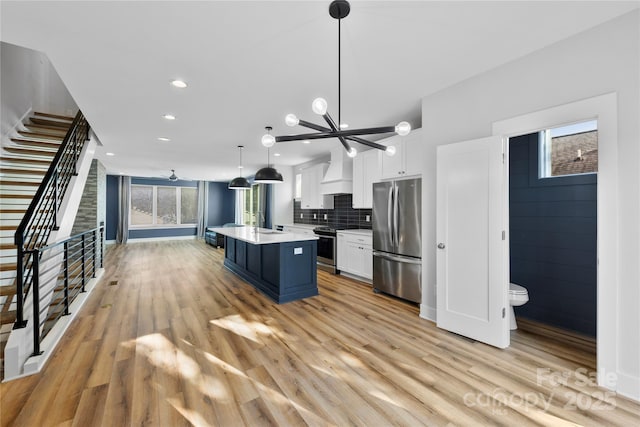 kitchen featuring white cabinetry, hanging light fixtures, stainless steel appliances, a kitchen island, and custom exhaust hood