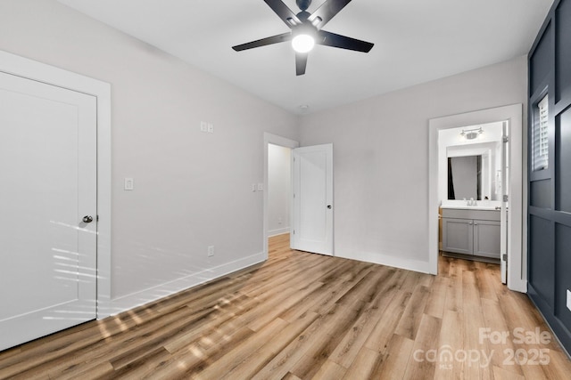 unfurnished bedroom featuring light wood-type flooring, baseboards, a sink, and ensuite bathroom