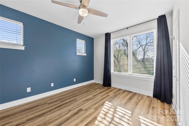 empty room with a ceiling fan, baseboards, and wood finished floors