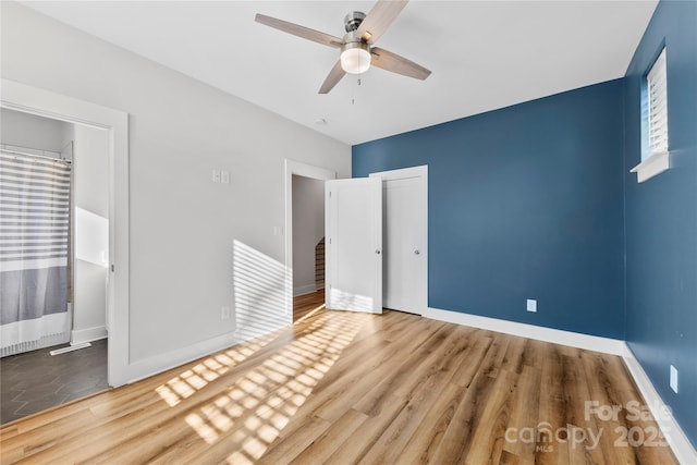 unfurnished bedroom featuring a ceiling fan, a closet, baseboards, and wood finished floors