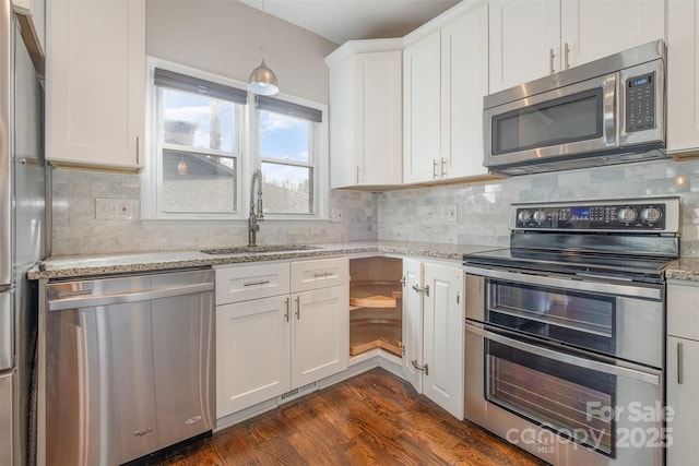 kitchen with sink, dark wood-type flooring, light stone counters, white cabinets, and appliances with stainless steel finishes