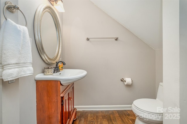 bathroom with vanity, hardwood / wood-style flooring, toilet, and lofted ceiling