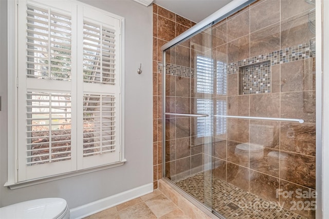 bathroom featuring tile patterned floors, toilet, and a shower with shower door