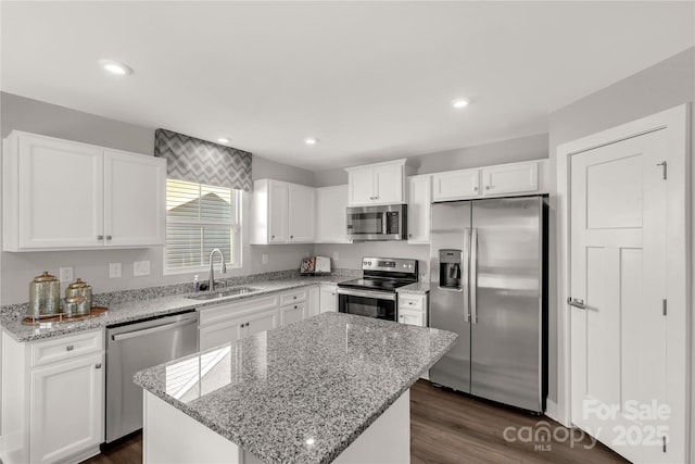 kitchen featuring light stone counters, stainless steel appliances, sink, white cabinets, and a kitchen island