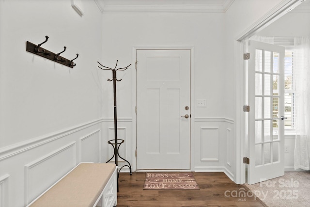 foyer featuring crown molding, a decorative wall, and wood finished floors