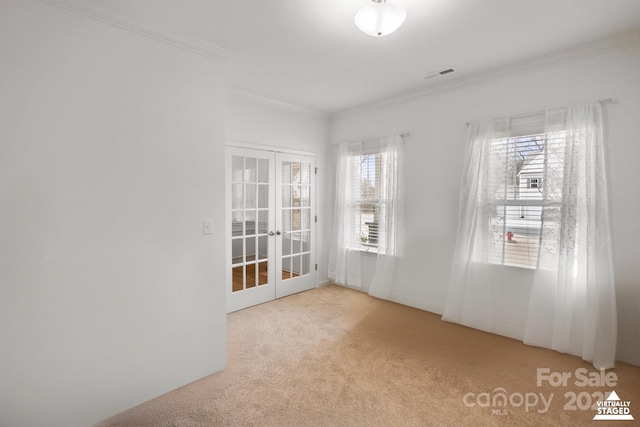 carpeted empty room featuring visible vents, ornamental molding, and french doors