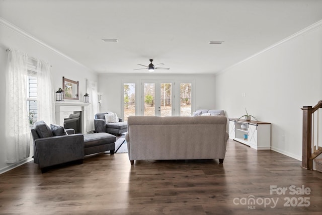 living area with dark wood-style flooring, crown molding, a fireplace, visible vents, and stairway