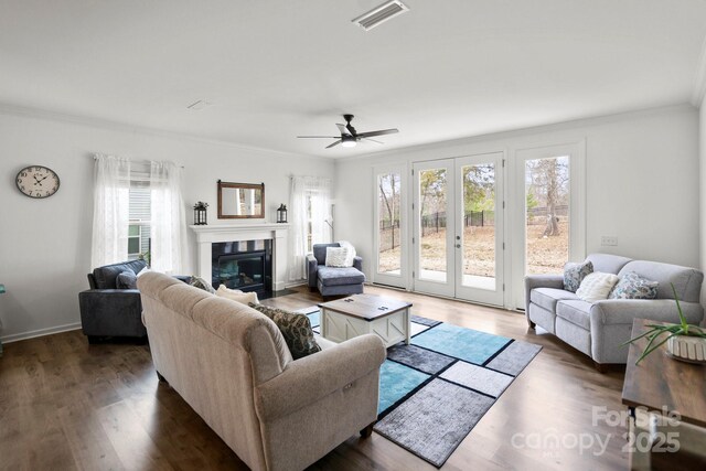 living room with a healthy amount of sunlight, visible vents, and crown molding