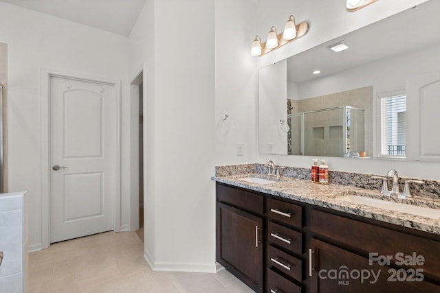 full bath featuring a sink, a shower stall, baseboards, and double vanity