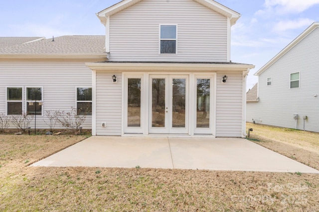 rear view of house with a yard, french doors, a patio area, and a shingled roof