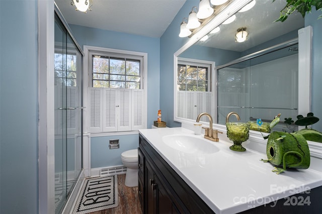 bathroom with vanity, a textured ceiling, hardwood / wood-style floors, toilet, and a shower with shower door