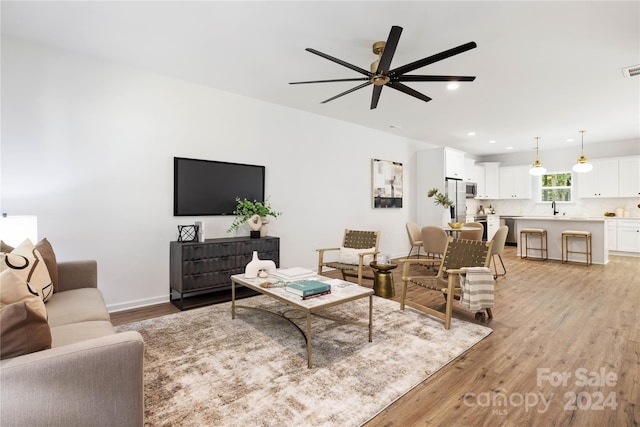 living room featuring light hardwood / wood-style flooring, ceiling fan, and sink