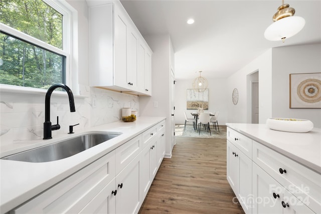 kitchen with white cabinetry, sink, hanging light fixtures, dark hardwood / wood-style floors, and decorative backsplash