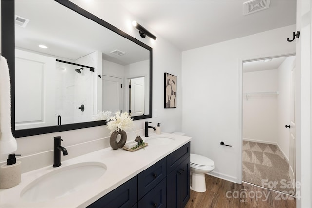 bathroom with a shower with door, vanity, wood-type flooring, and toilet