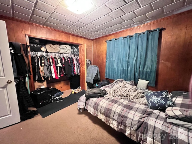 carpeted bedroom with a closet and wooden walls