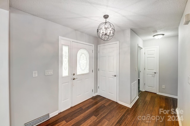 entryway with dark hardwood / wood-style floors, a textured ceiling, and a chandelier