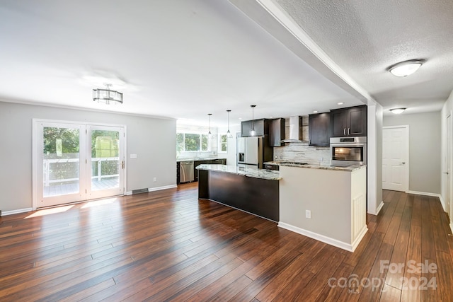 kitchen featuring tasteful backsplash, wall chimney exhaust hood, dark brown cabinets, stainless steel appliances, and dark hardwood / wood-style floors