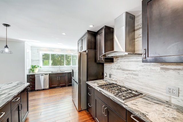 kitchen with light stone countertops, appliances with stainless steel finishes, light hardwood / wood-style flooring, and wall chimney exhaust hood