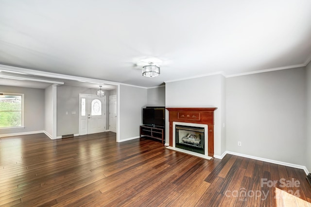 unfurnished living room with dark hardwood / wood-style floors, an inviting chandelier, and ornamental molding