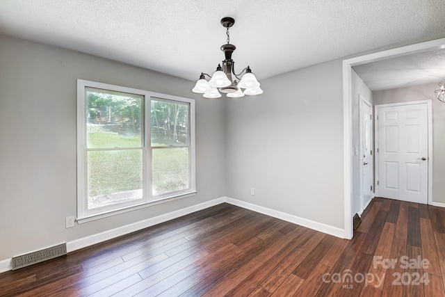 unfurnished room with a textured ceiling, dark hardwood / wood-style floors, and an inviting chandelier