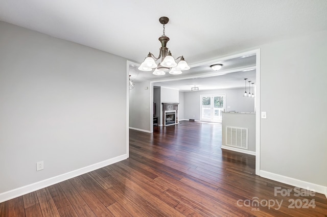 unfurnished dining area with a fireplace, dark hardwood / wood-style flooring, and a chandelier