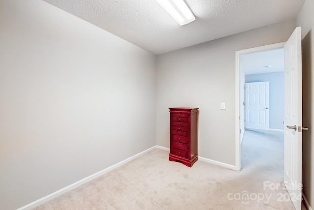 unfurnished room featuring light colored carpet and a textured ceiling