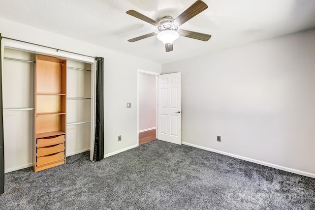 unfurnished bedroom with dark colored carpet, ceiling fan, a textured ceiling, and a closet