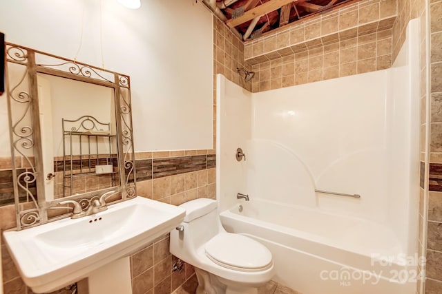 full bathroom with sink, toilet, tile walls, and shower / washtub combination