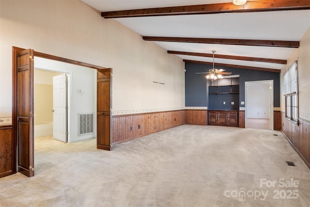 empty room featuring wood walls, light colored carpet, lofted ceiling, and ceiling fan