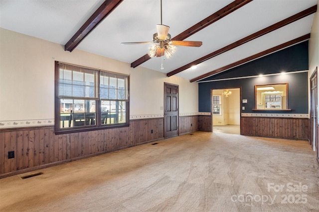 unfurnished living room featuring light carpet, lofted ceiling with beams, wood walls, and ceiling fan with notable chandelier