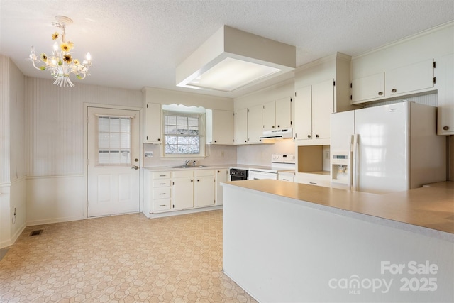 kitchen with a textured ceiling, white appliances, white cabinetry, and pendant lighting