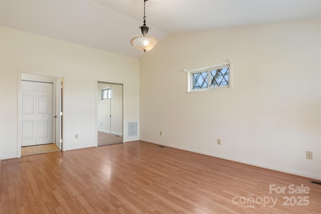 unfurnished room featuring vaulted ceiling and light hardwood / wood-style floors