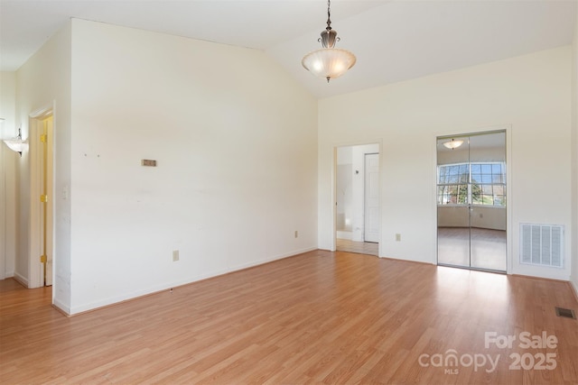 spare room featuring light hardwood / wood-style flooring and vaulted ceiling