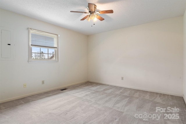 empty room featuring a textured ceiling, ceiling fan, electric panel, and light colored carpet