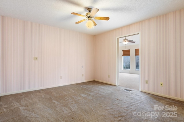 carpeted empty room featuring ceiling fan and a textured ceiling