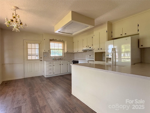 9566 Wilson Rd, Hildebran, NC 28637 - kitchen featuring under cabinet range hood, white appliances, a textured ceiling, dark wood-type flooring, and a chandelier