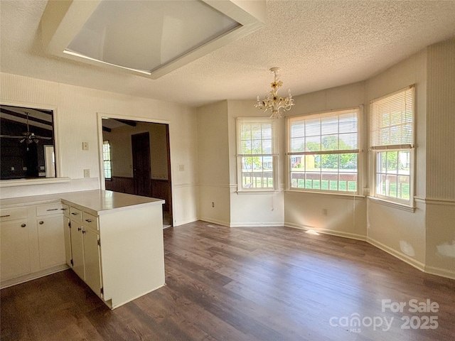 9566 Wilson Rd, Hildebran, NC 28637 - kitchen featuring a textured ceiling, dark wood-style flooring, a chandelier, light countertops, and a peninsula
